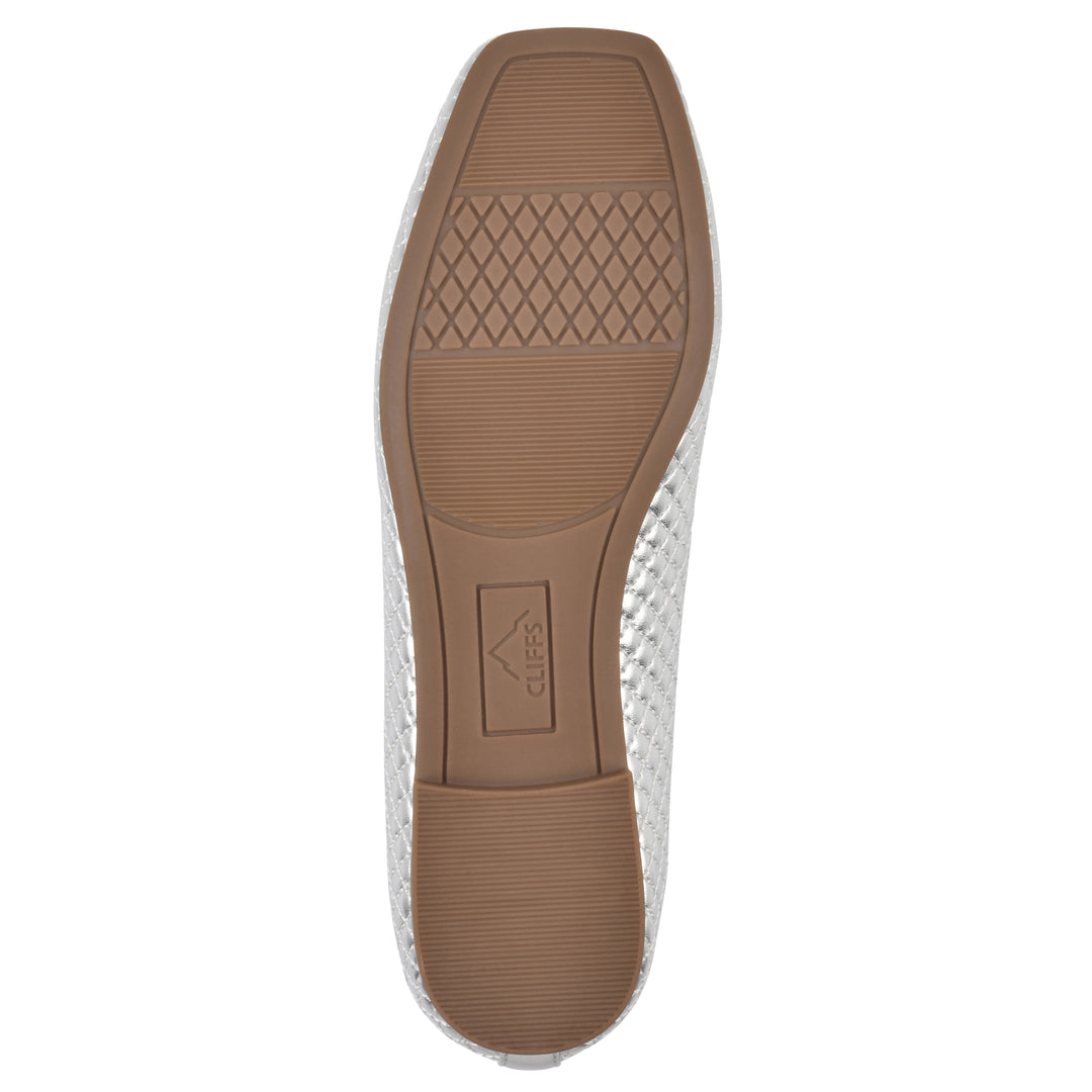 Sole view of a silver quilted pattern flat with small, centered, silver bow and a brown sole