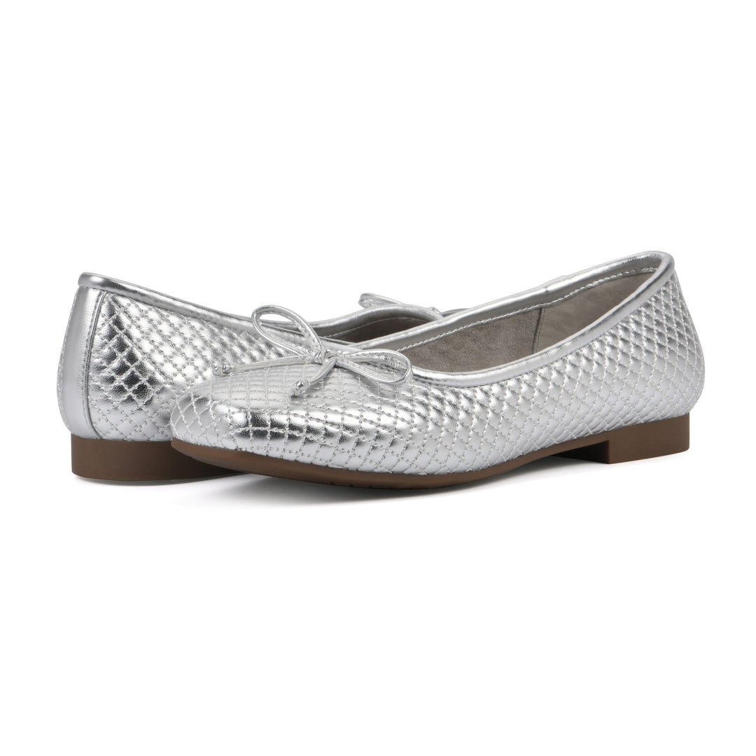 Angle view of a pair of silver quilted pattern flats with small, centered, silver bow and a brown sole