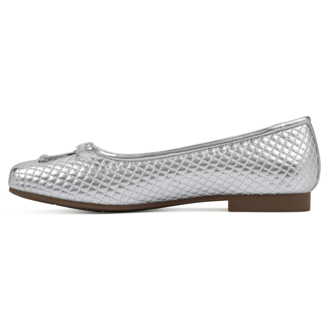 Side view of a silver quilted pattern flat with small, centered, silver bow and a brown sole