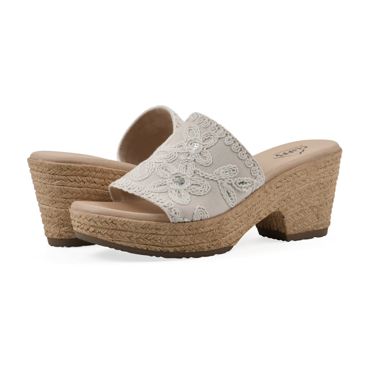 Angle view of a pair of ivory wedge sandals with cream embroidered floral pattern and a braided rope-style sole