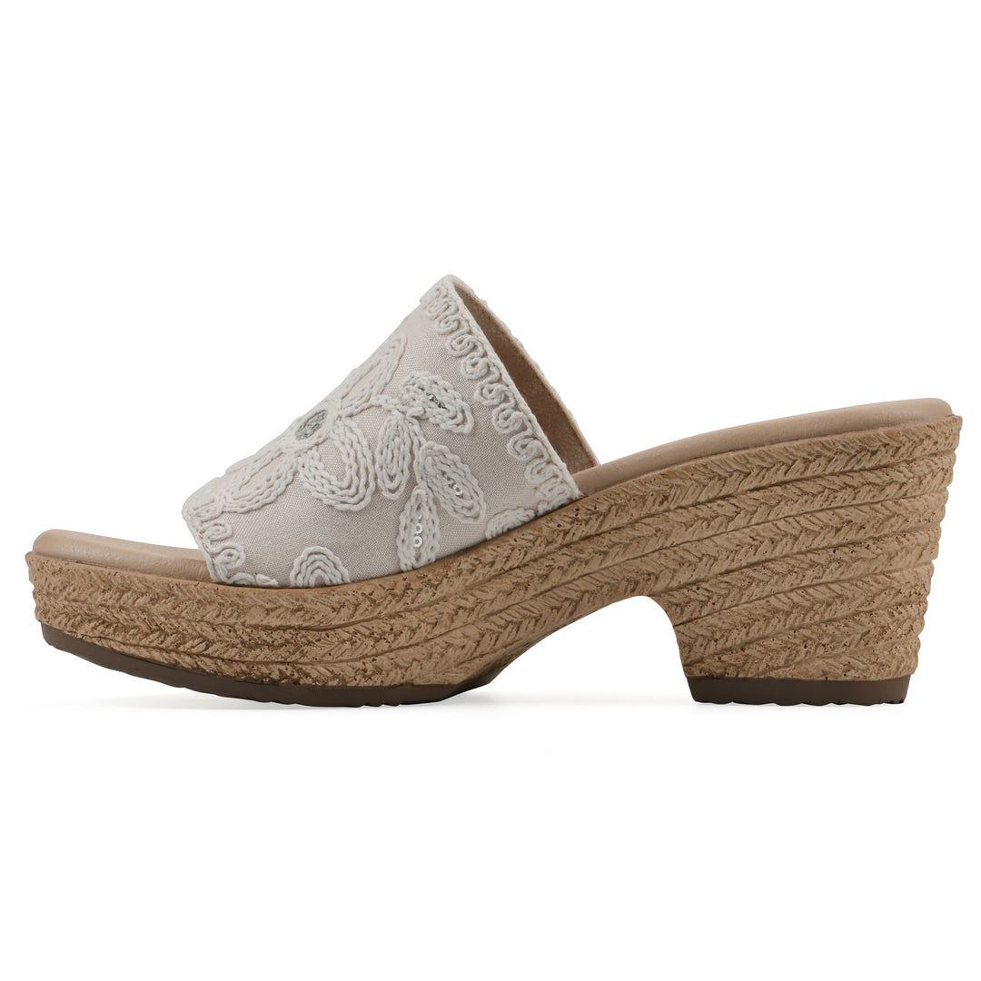Side view of an ivory wedge sandal with cream embroidered floral pattern and a braided rope-style sole