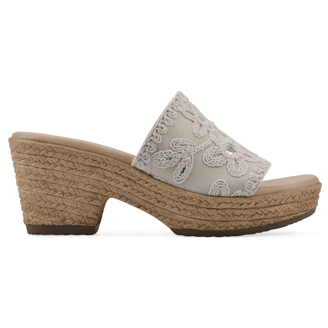 Side view of an ivory wedge sandal with cream embroidered floral pattern and a braided rope-style sole