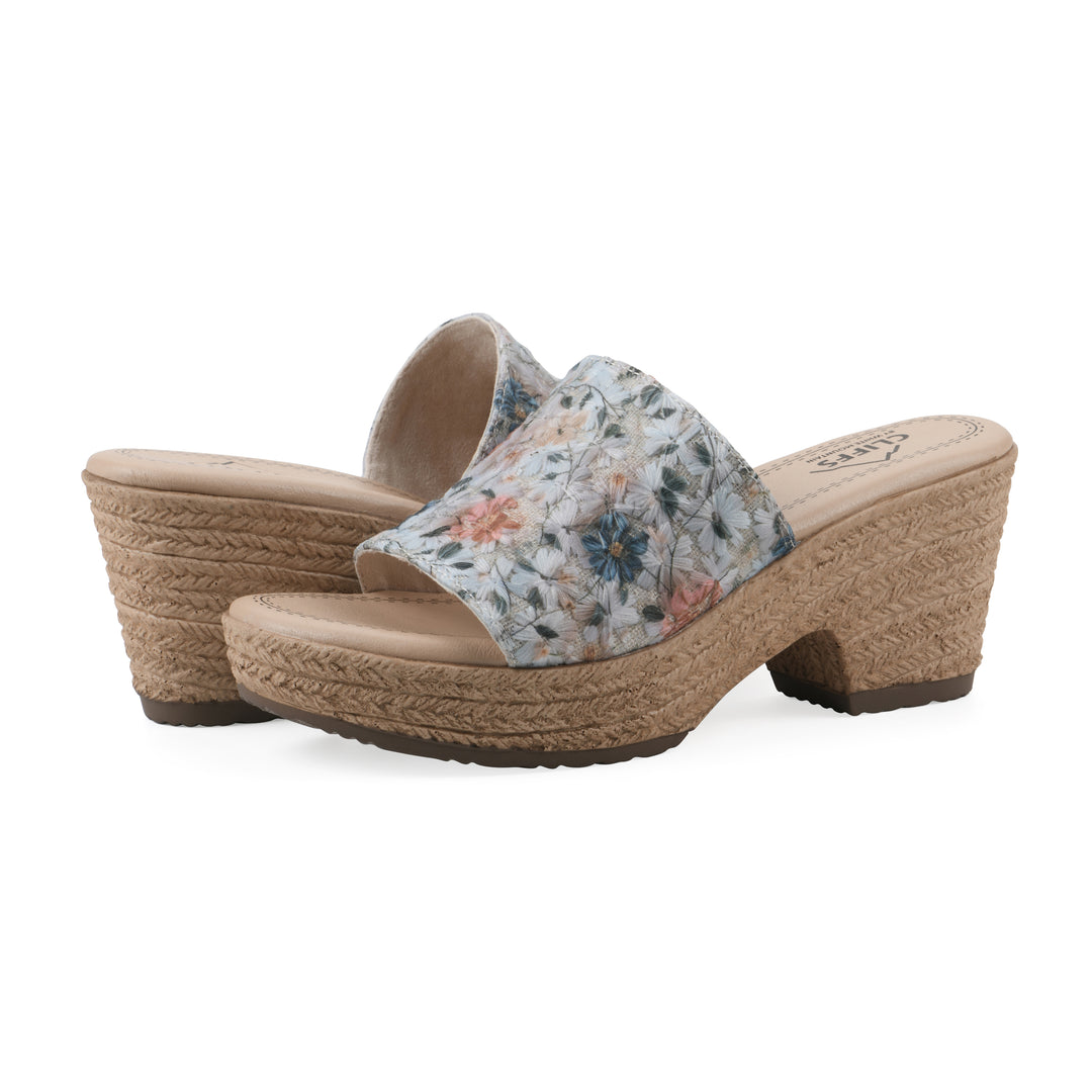 Angle view of a pair of muted watercolor floral pattern wedge sandals with a braided rope-style sole