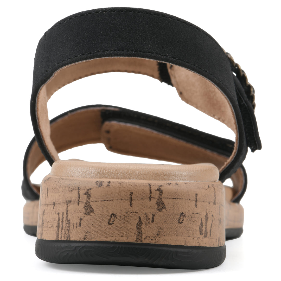 Rear view of a black sandal with double adjustable straps, circular buckle embellishment, and low cork print wedge 