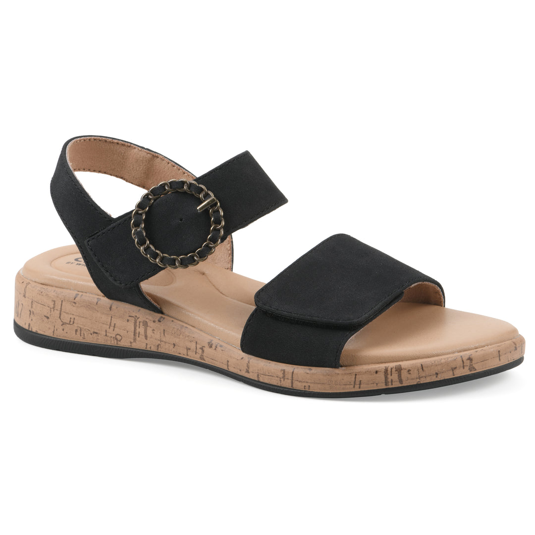Angle view of a black sandal with double adjustable straps, circular buckle embellishment, and low cork print wedge 