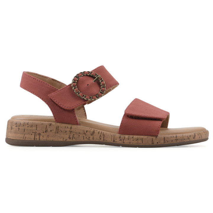 Side view of a dusty orange sandal with double adjustable straps, circular buckle embellishment, and low cork print wedge 