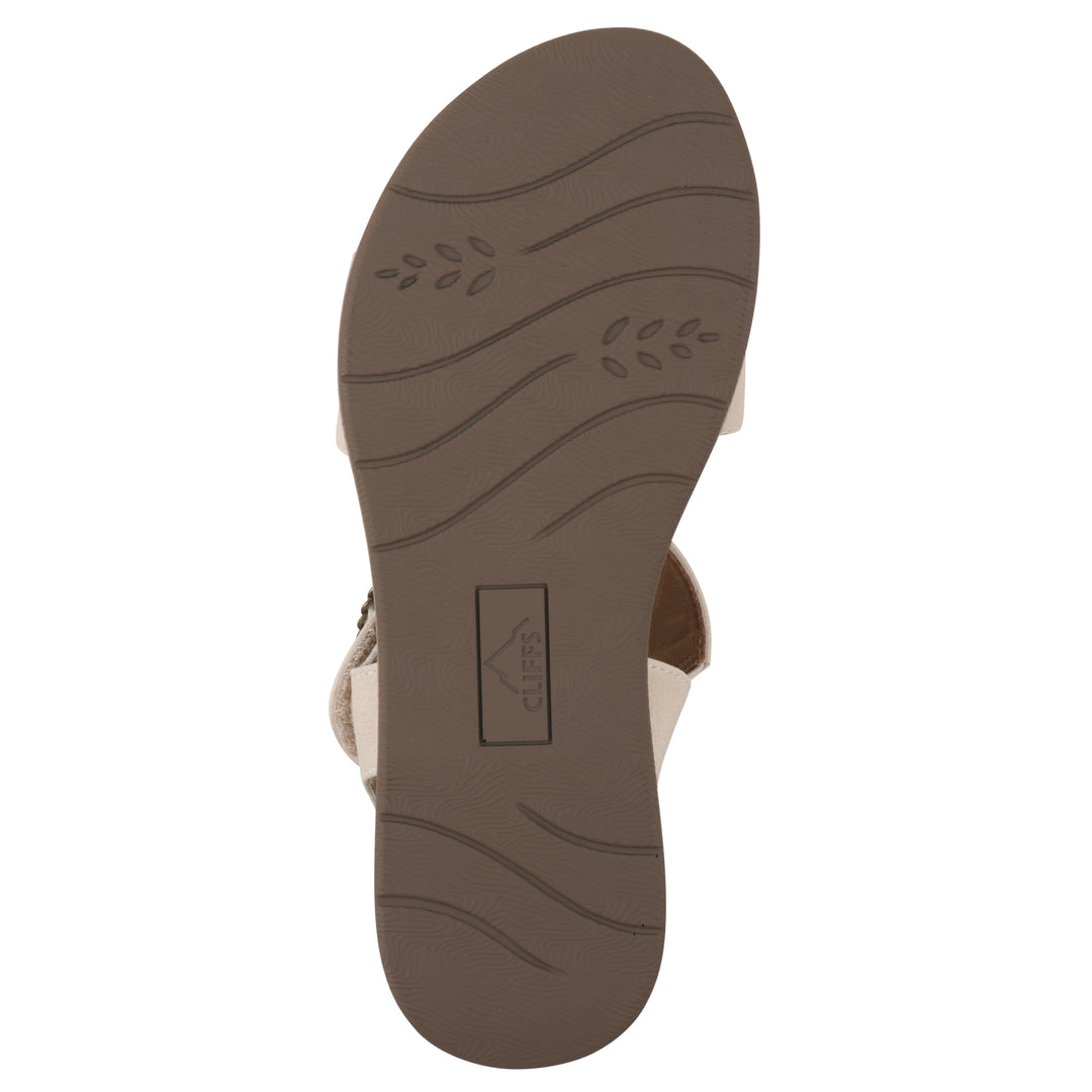 Sole view of a cream sandal with double adjustable straps, circular buckle embellishment, and low cork print wedge 