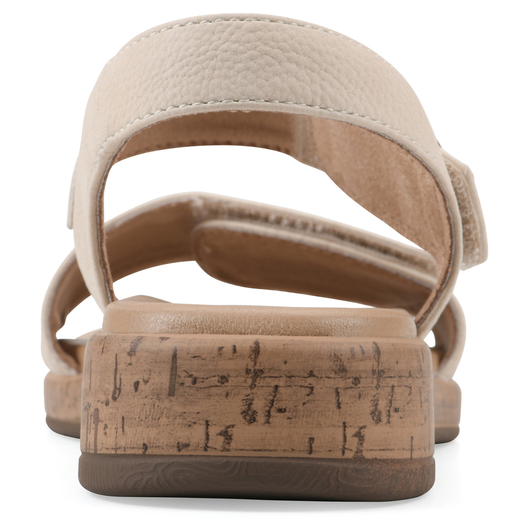 Rear view of a cream sandal with double adjustable straps, circular buckle embellishment, and low cork print wedge 