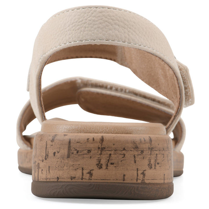 Rear view of a cream sandal with double adjustable straps, circular buckle embellishment, and low cork print wedge 