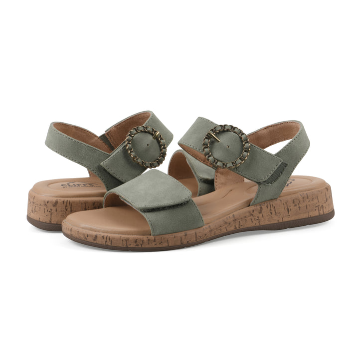 Angle view of a pair of sage sandals with double adjustable straps, circular buckle embellishment, and low cork print wedge 