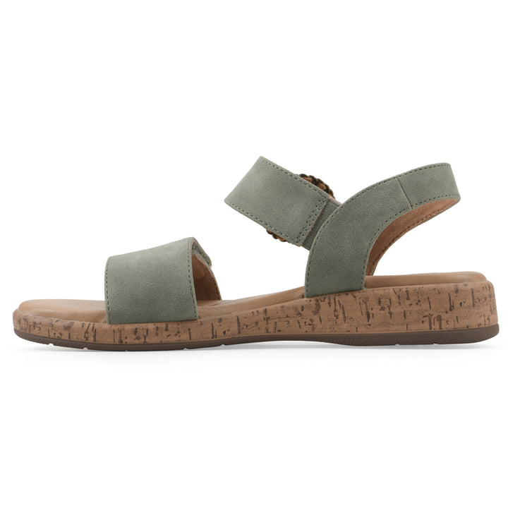 Side view of a sage sandal with double adjustable straps, circular buckle embellishment, and low cork print wedge 
