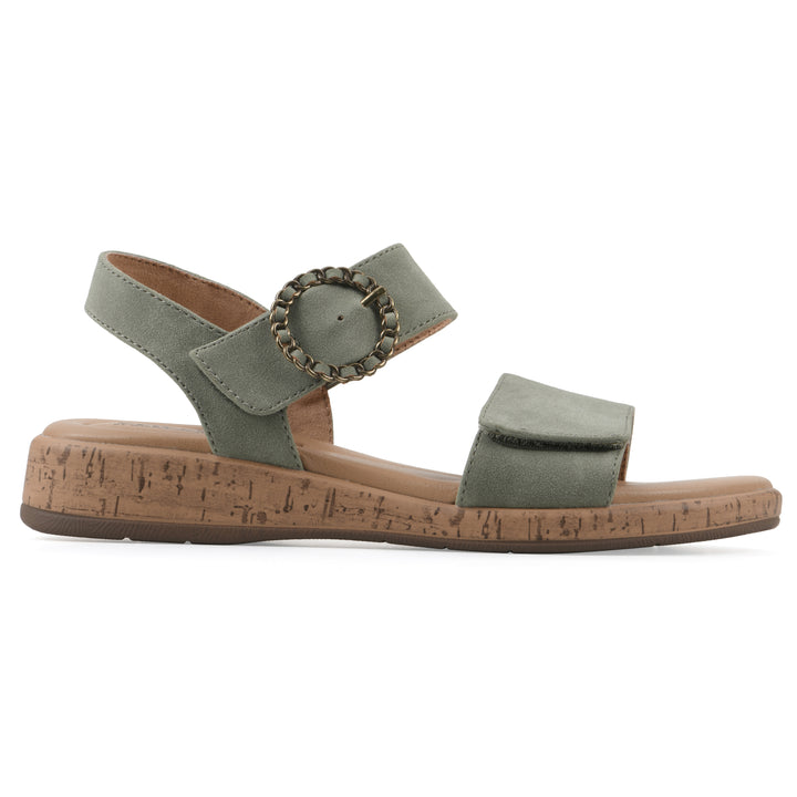 Side view of a sage sandal with double adjustable straps, circular buckle embellishment, and low cork print wedge 