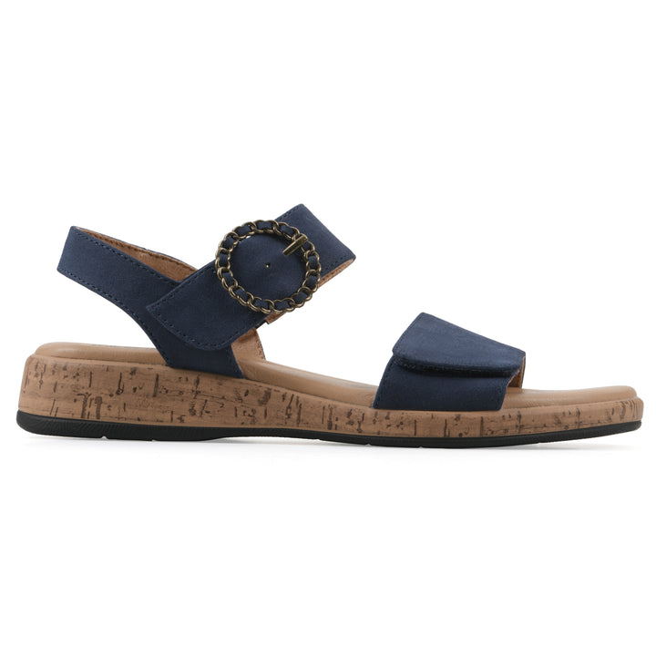 Side view of a dark blue sandal with double adjustable straps, circular buckle embellishment, and low cork print wedge 