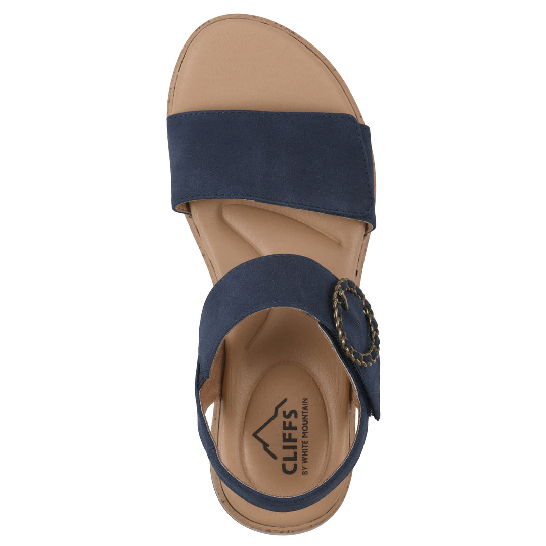Top view of a dark blue sandal with double adjustable straps, circular buckle embellishment, and low cork print wedge 