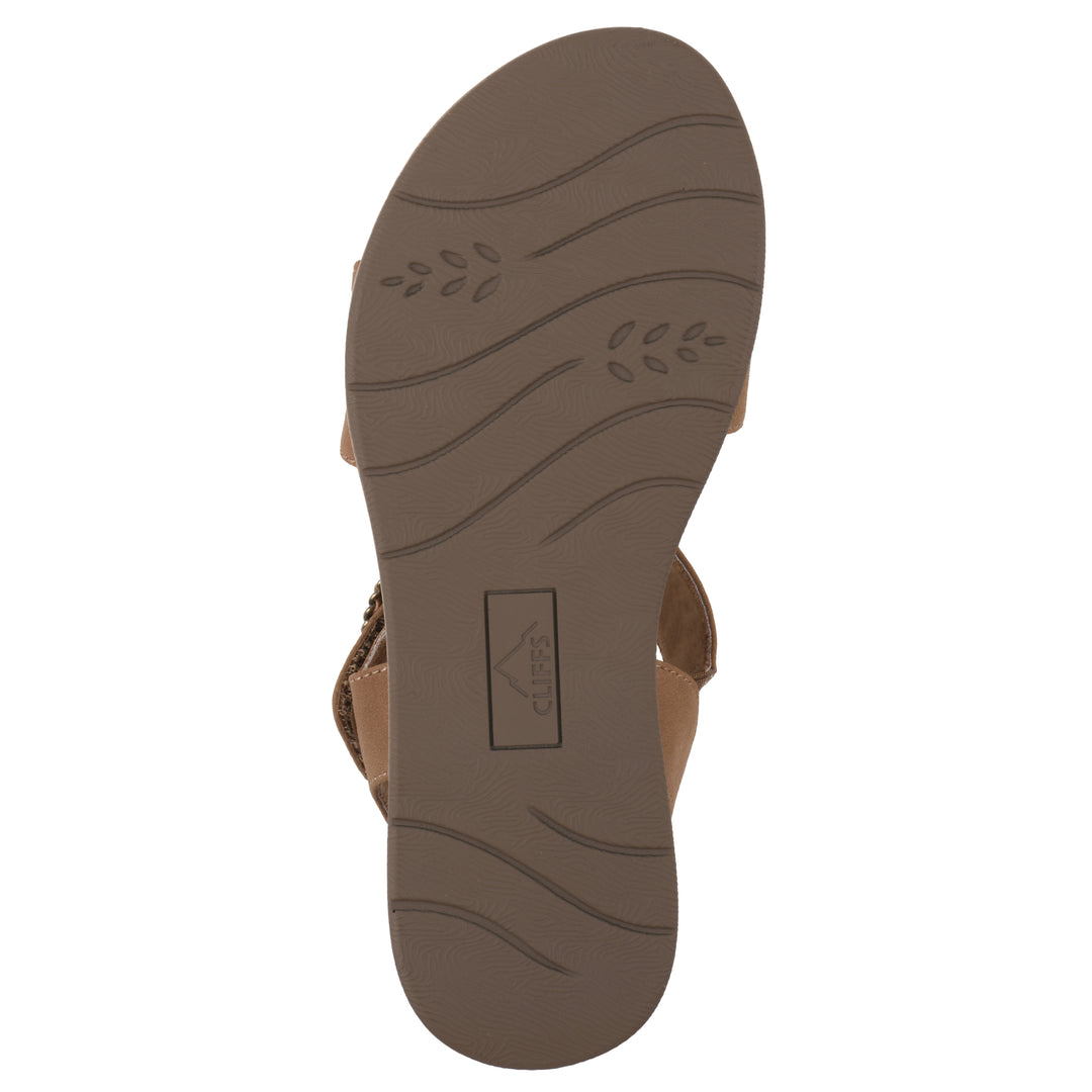 Sole view of a tan sandal with double adjustable straps, circular buckle embellishment, and low cork print wedge 