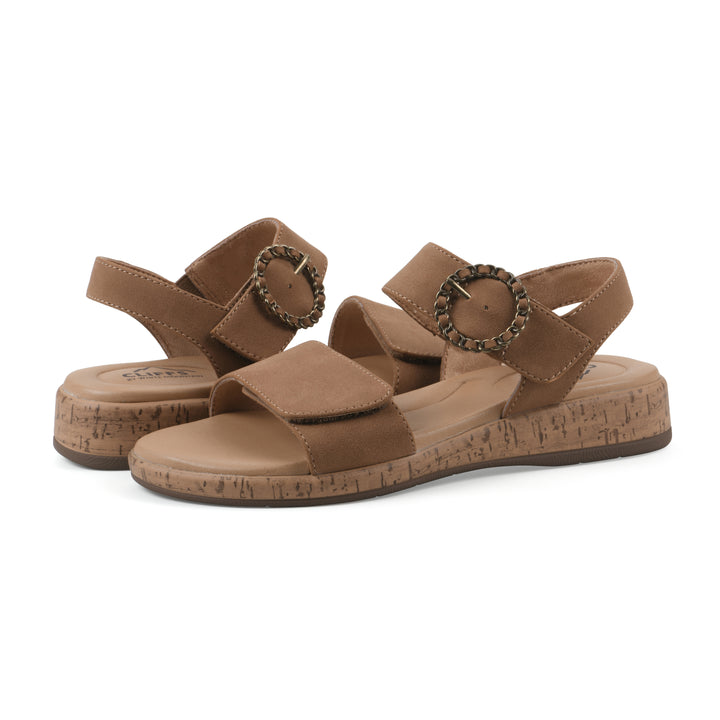 Angle view of a pair of tan sandals with double adjustable straps, circular buckle embellishment, and low cork print wedge 