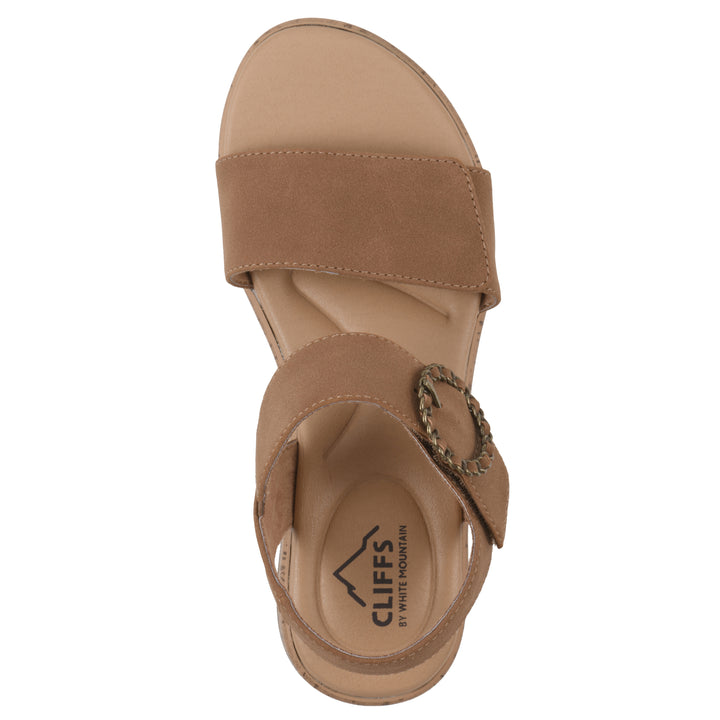Top view of a tan sandal with double adjustable straps, circular buckle embellishment, and low cork print wedge 