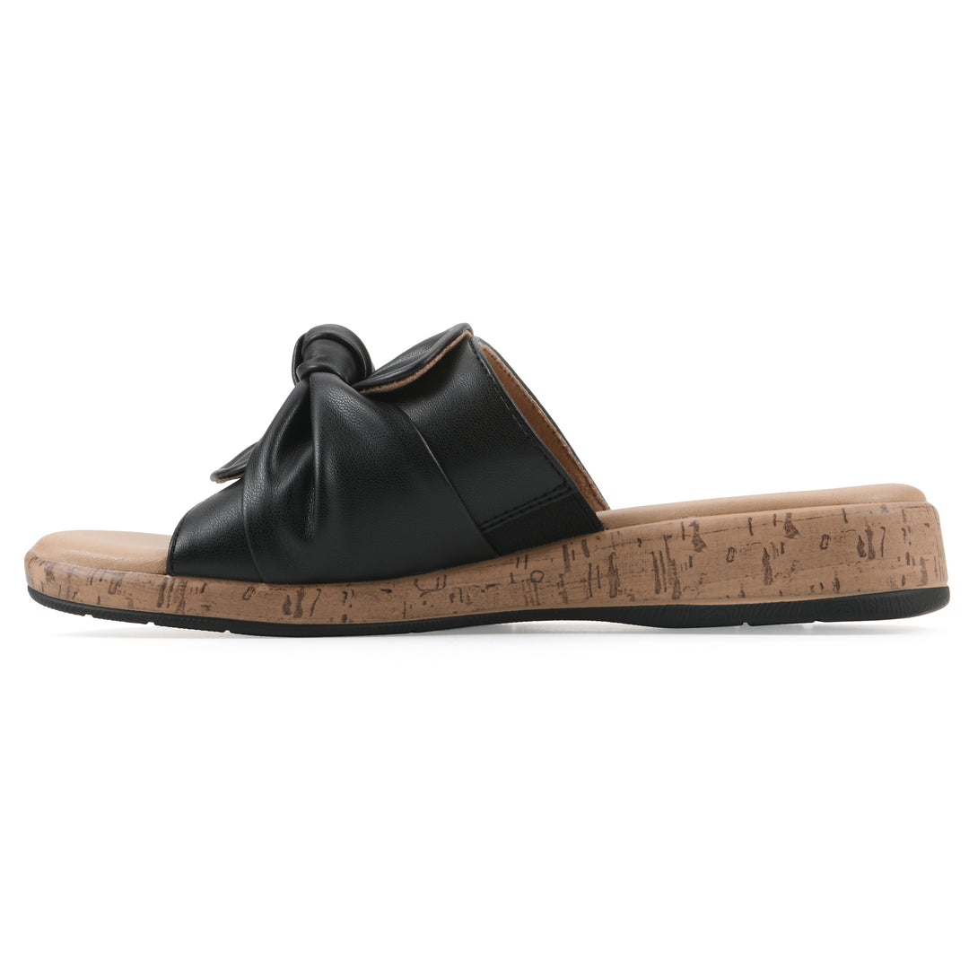 Side view of a black faux leather sandal with centered twist, and cork-print sole design
