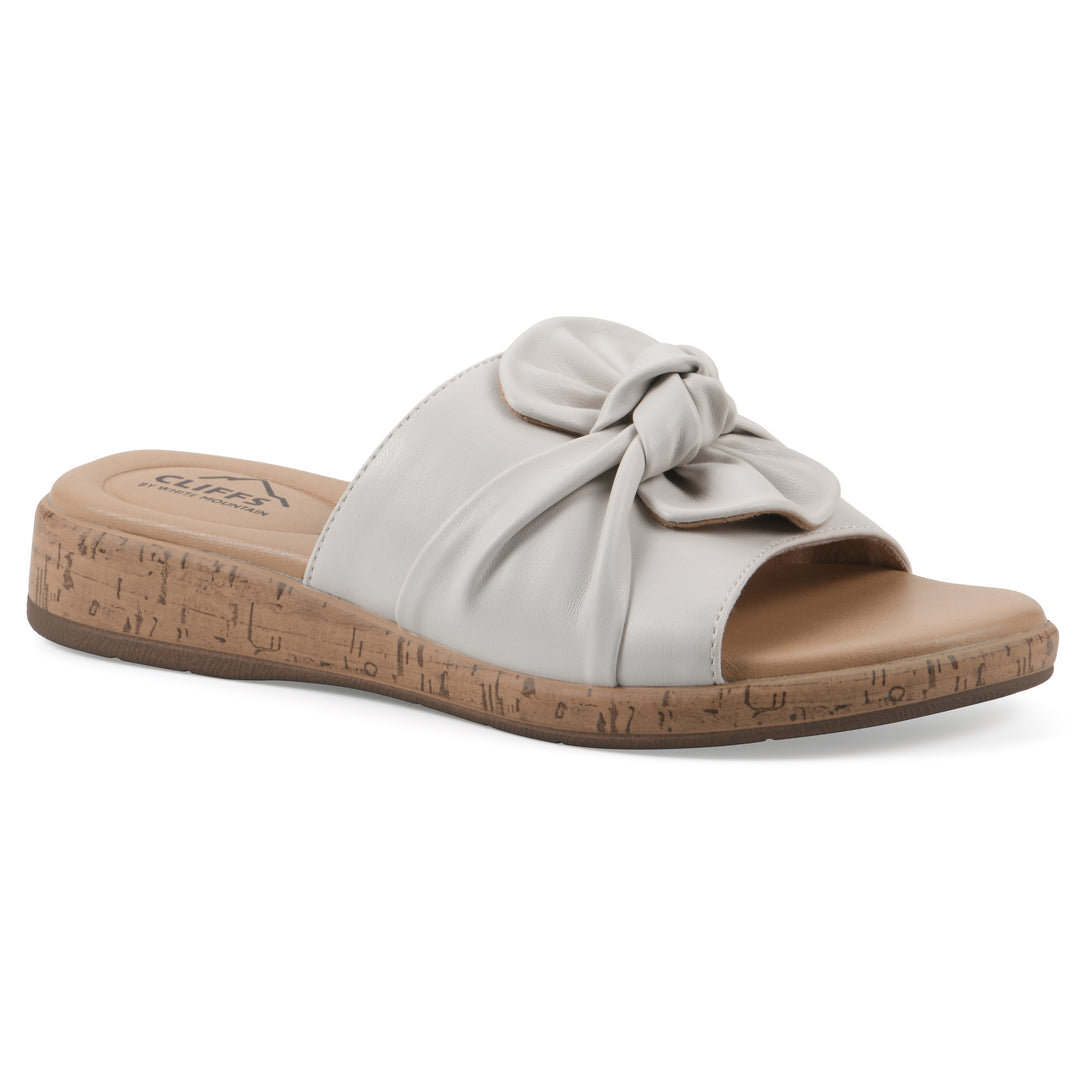 Angle view of a white faux leather sandal with centered twist, and cork-print sole design