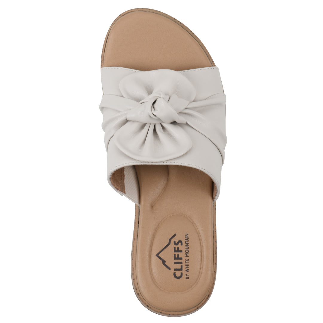 Top view of a white faux leather sandal with centered twist, and cork-print sole design