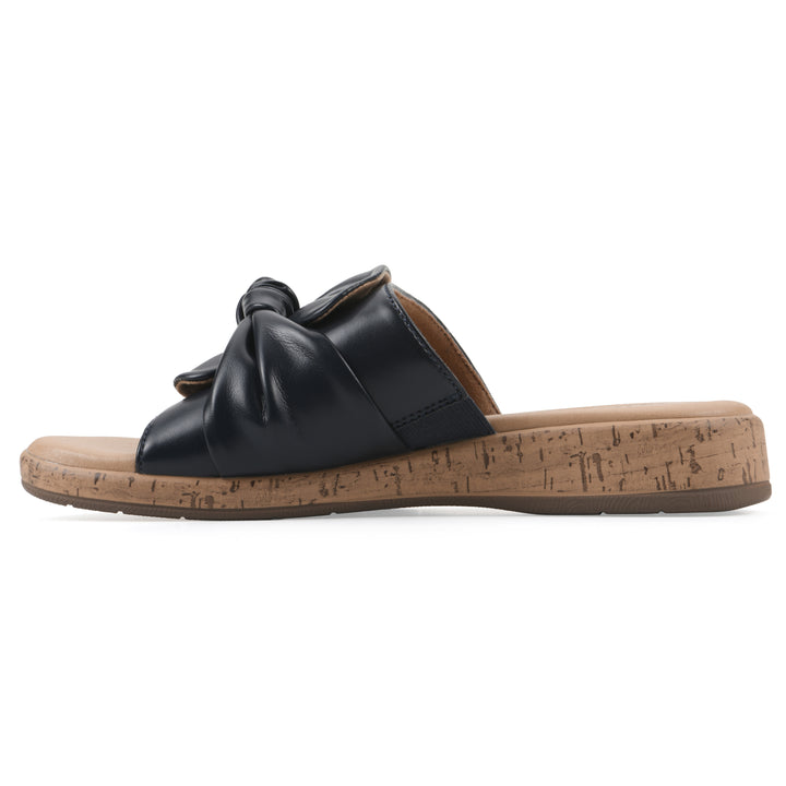 Side view of a black faux leather sandal with centered twist, and cork-print sole design