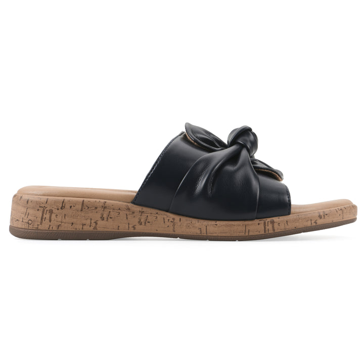 Side view of a black faux leather sandal with centered twist, and cork-print sole design