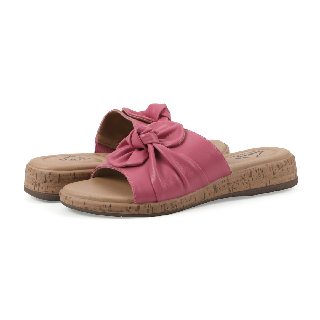 Angle view of a pair of mauve faux leather sandals with centered twist, and cork-print sole design