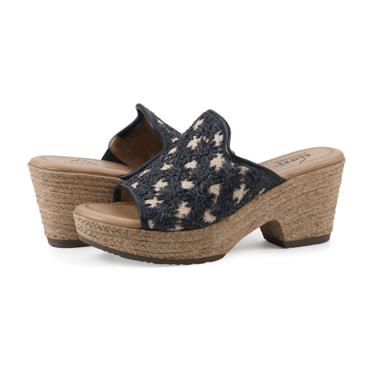 Angle view of a pair of dark blue embroidered fabric wedge sandals with a braided rope-style sole