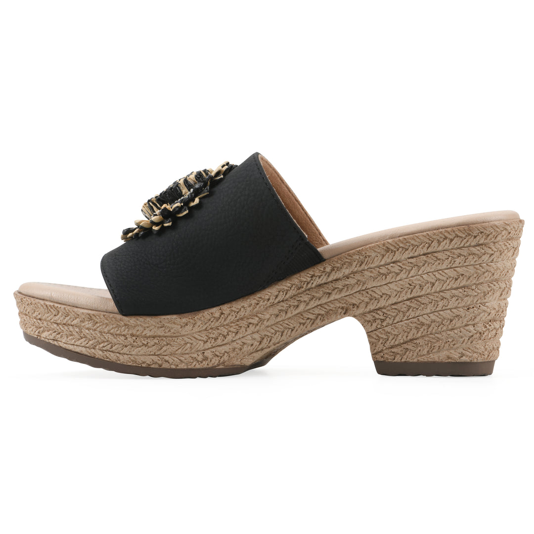Side view of a black, backless wedge sandal with centered sunflower embellishment, and braided rope style heel