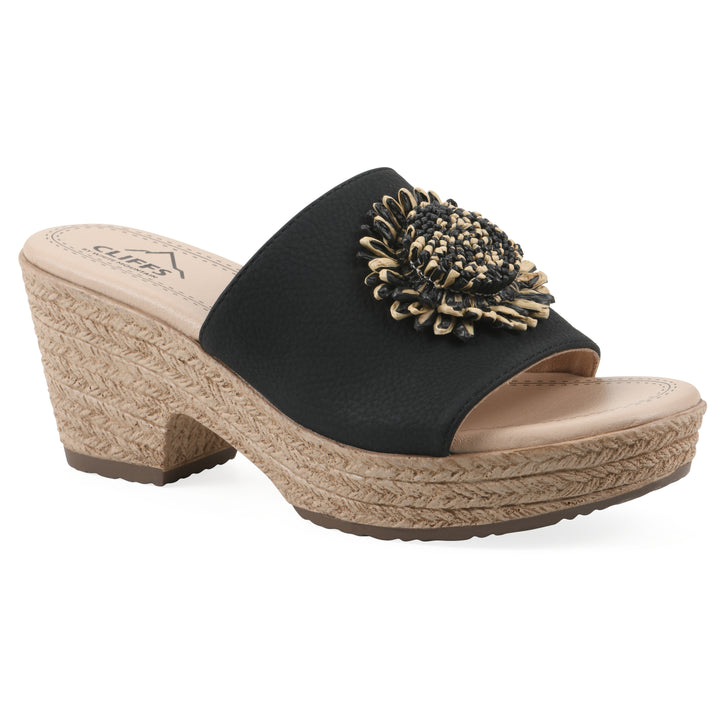Angle view of a black, backless wedge sandal with centered sunflower embellishment, and braided rope style heel