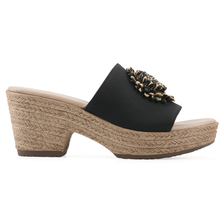 Side view of a black, backless wedge sandal with centered sunflower embellishment, and braided rope style heel