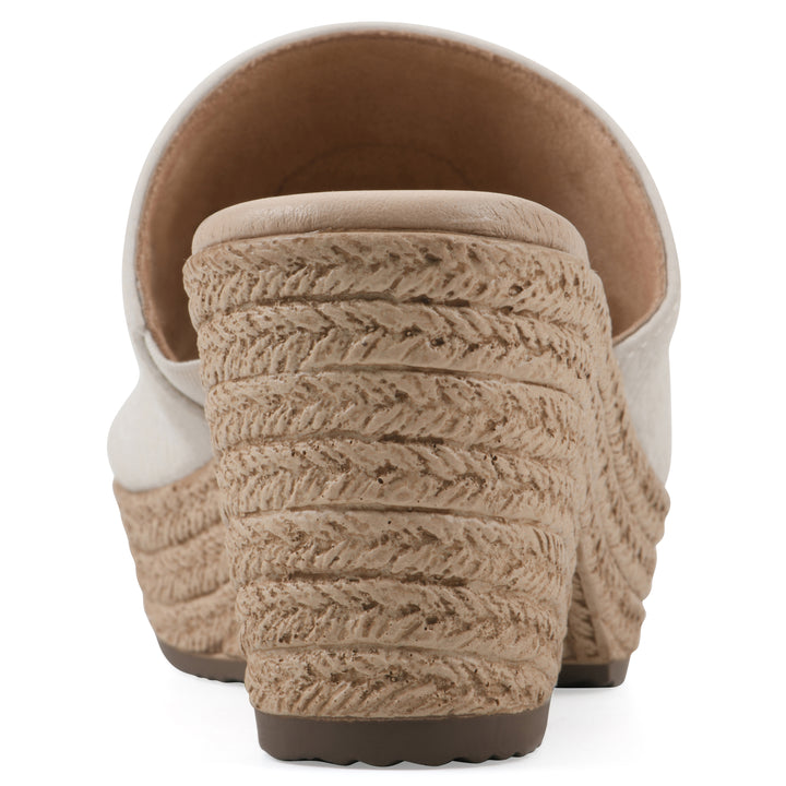 Rear view of a cream, backless wedge sandal with centered sunflower embellishment, and braided rope style heel