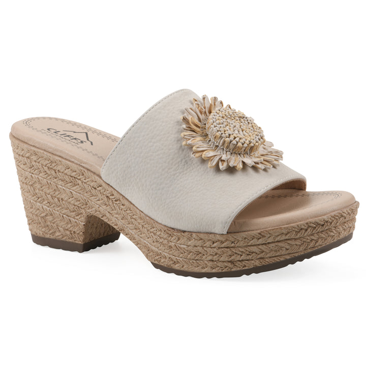 Angle view of a cream, backless wedge sandal with centered sunflower embellishment, and braided rope style heel