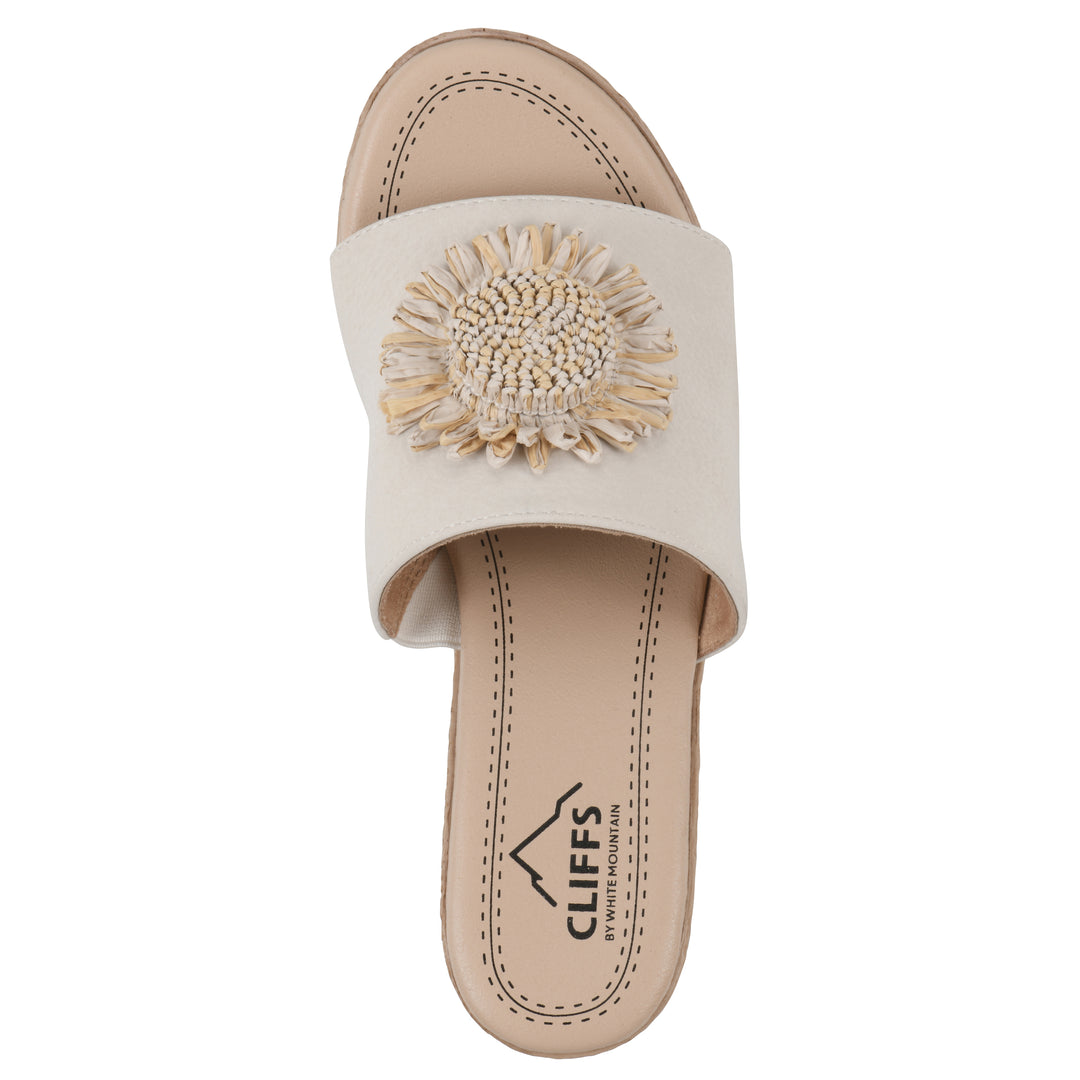 Top view of a cream, backless wedge sandal with centered sunflower embellishment, and braided rope style heel