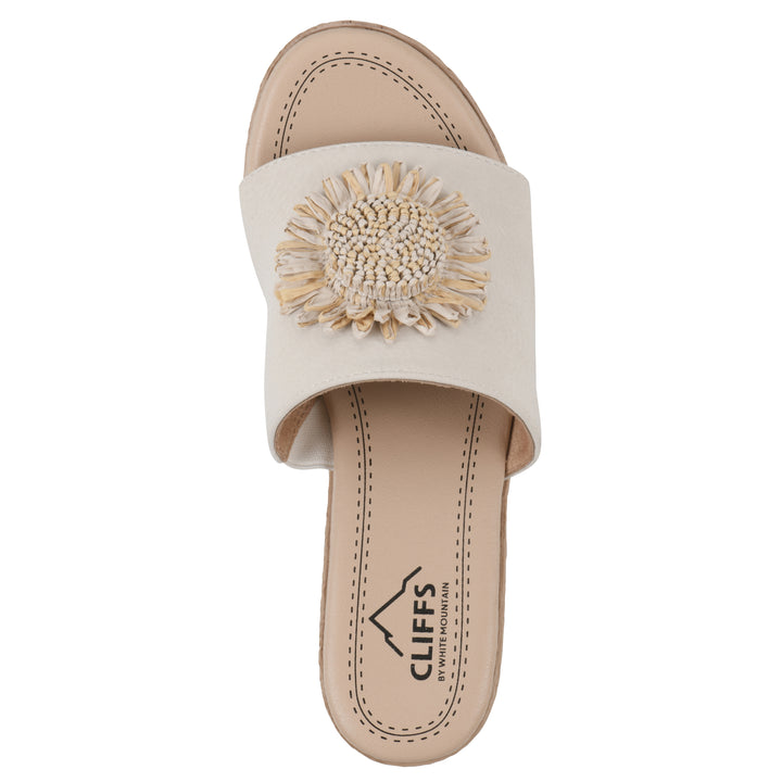 Top view of a cream, backless wedge sandal with centered sunflower embellishment, and braided rope style heel