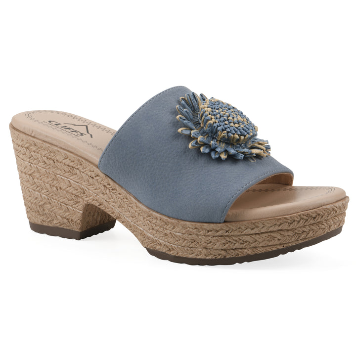 Angle view of a blue, backless wedge sandal with centered sunflower embellishment, and braided rope style heel