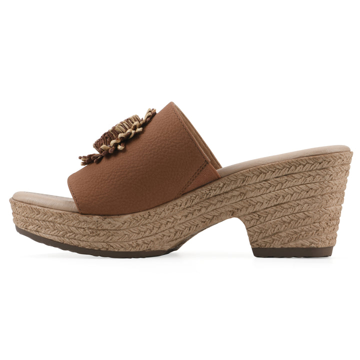 Side view of a brown, backless wedge sandal with centered sunflower embellishment, and braided rope style heel