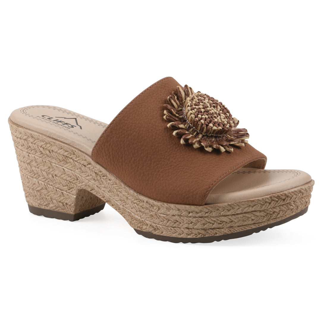 Angle view of a brown, backless wedge sandal with centered sunflower embellishment, and braided rope style heel