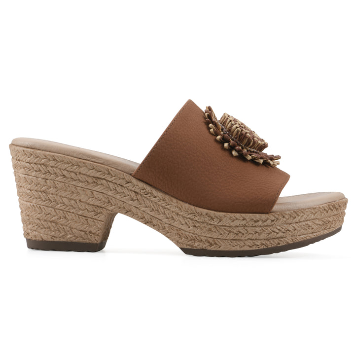Side view of a brown, backless wedge sandal with centered sunflower embellishment, and braided rope style heel