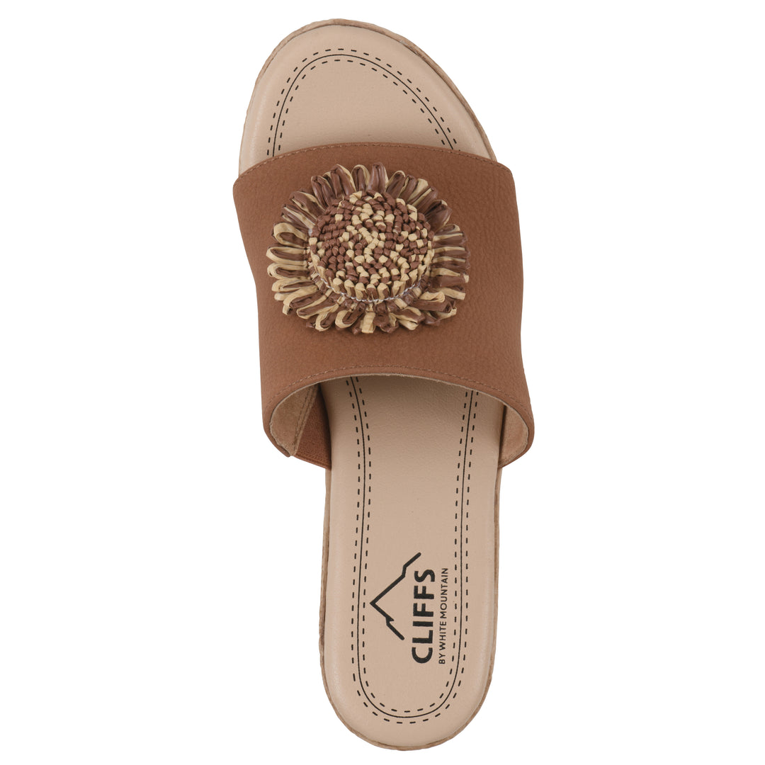 Top view of a brown, backless wedge sandal with centered sunflower embellishment, and braided rope style heel