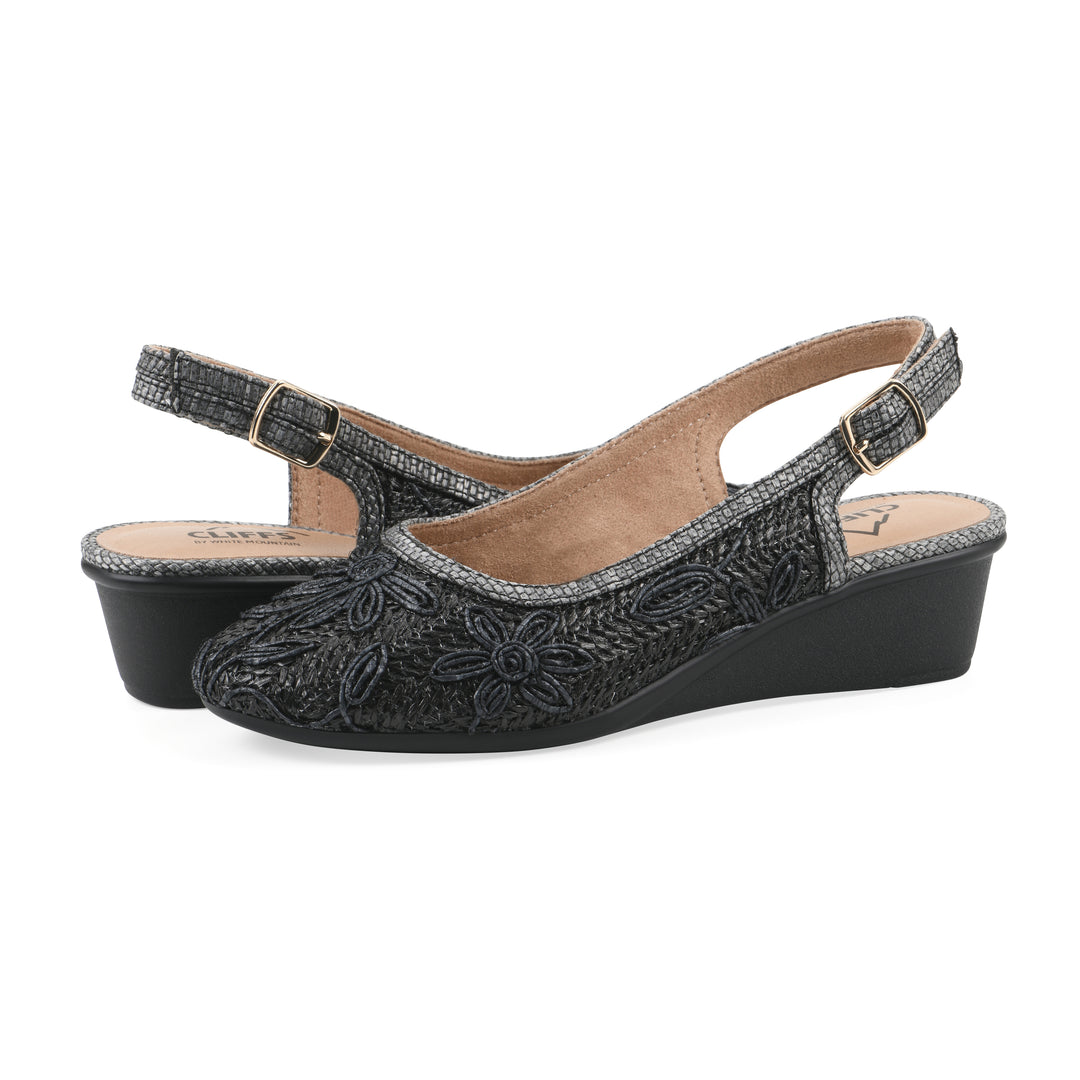 Angle view of a pair of woven, black, raffia slingbacks with black floral detailing and an adjustable heel strap