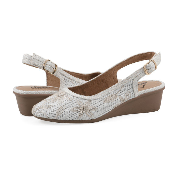 Angle view of a pair of woven, white, raffia slingbacks with white floral detailing and an adjustable heel strap
