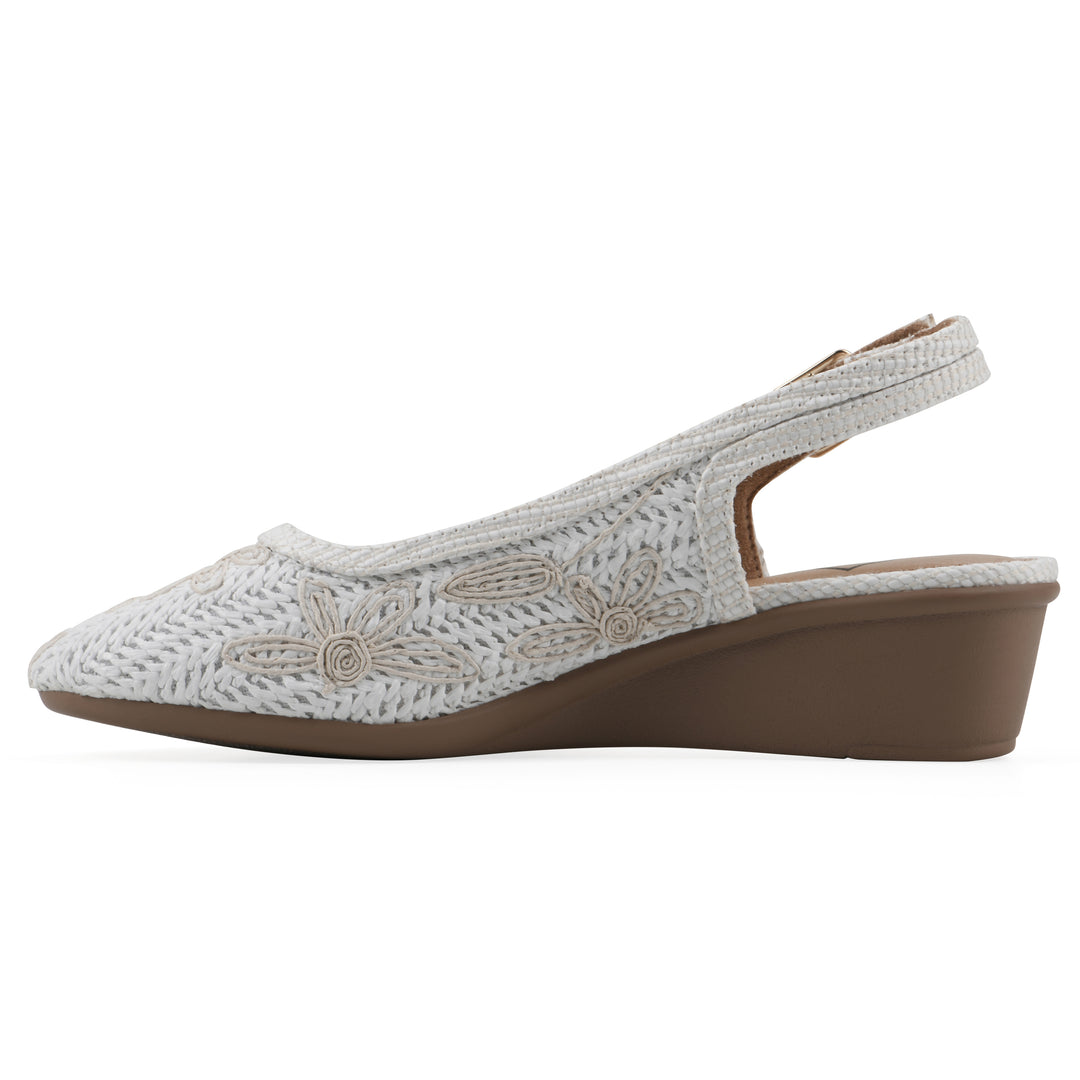 Side view of a woven, white, raffia slingback with white floral detailing and an adjustable heel strap