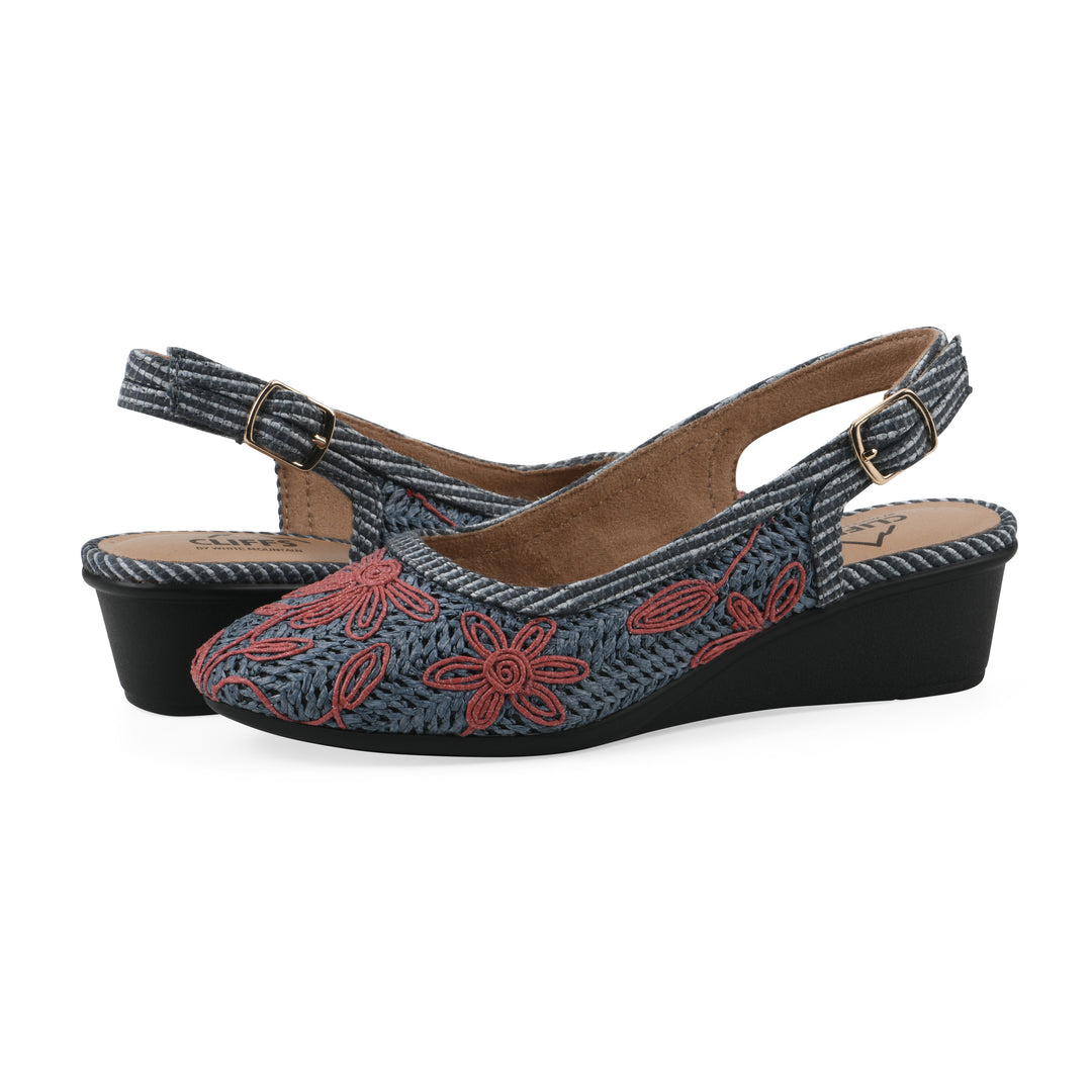Angle view of a pair of woven, blue, raffia slingbacks with muted red floral detailing and an adjustable heel strap