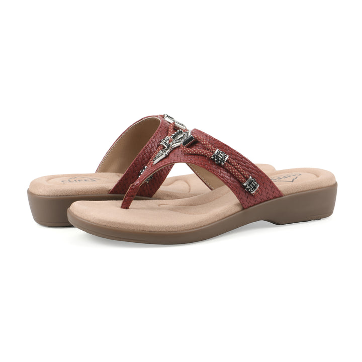 Angle view of a pair of brick red thong sandals with silver bead embellishments and a tan sole