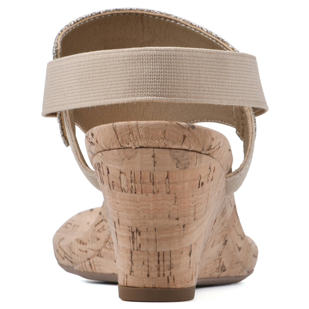 Rear view of a light gold fabric thong wedge sandal with cork heel, and elastic ankle strap