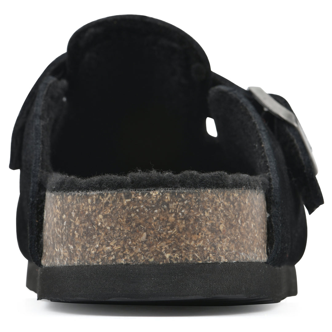 Rear view of a black suede clog with black faux shearling lining, a metal buckle on an adjustable strap, and a brown sole with black bottom
