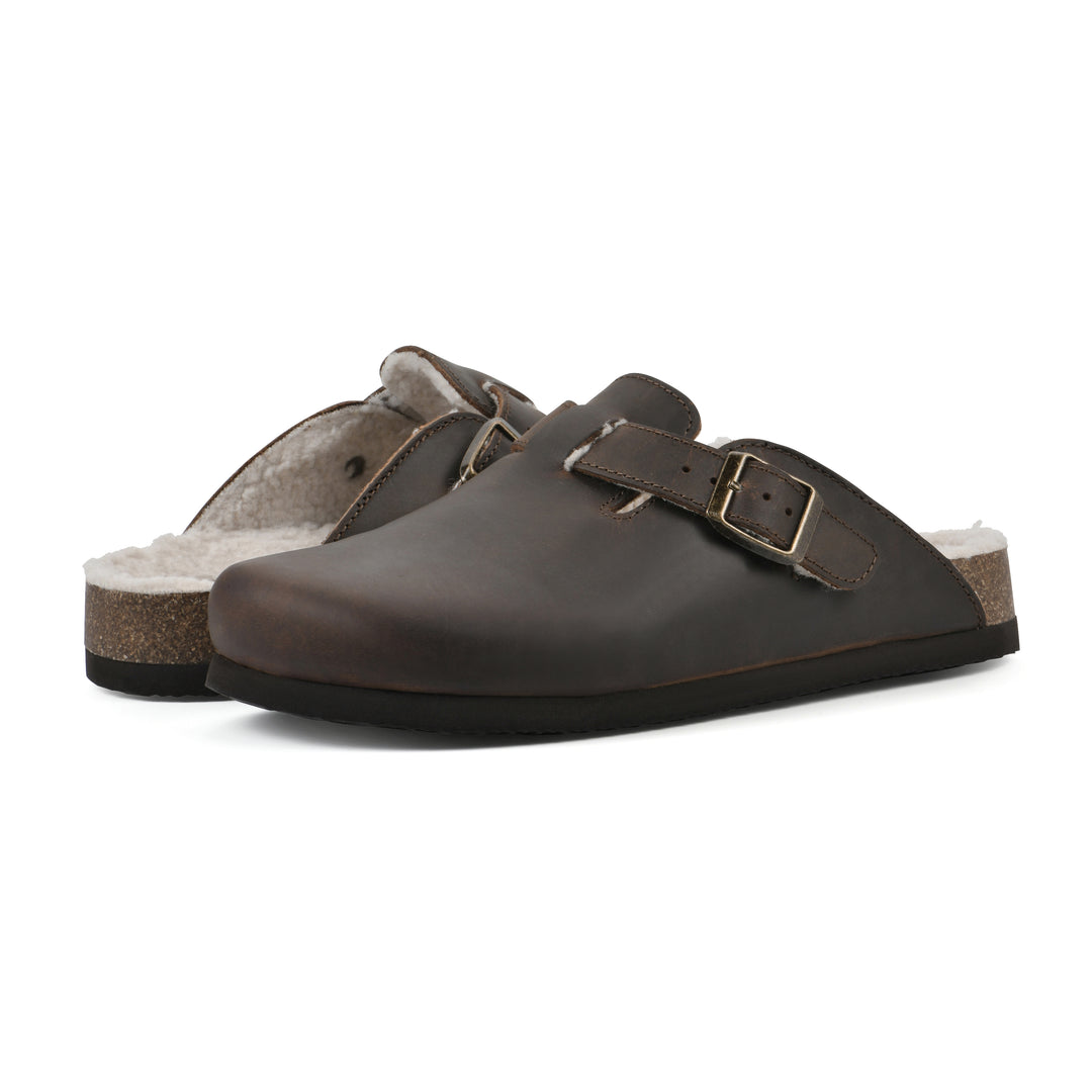 Angle view of a pair of brown leather clogs with white faux shearling lining, a metal buckle on an adjustable strap, and a brown sole with black bottom