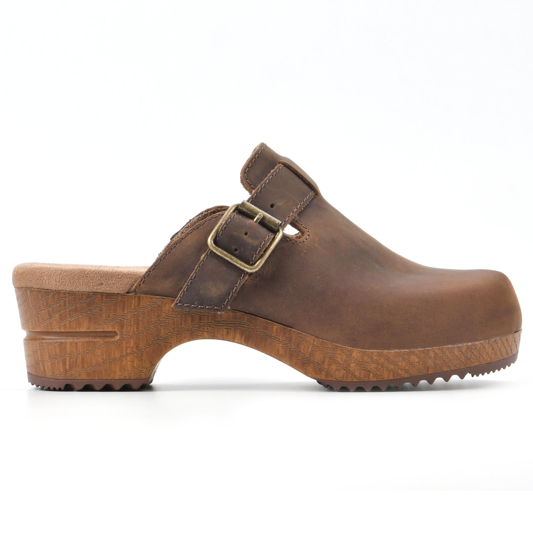 Side view of a backless brown leather clog with adjustable buckle and wood style heel