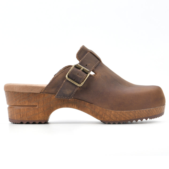 Side view of a backless brown leather clog with adjustable buckle and wood style heel